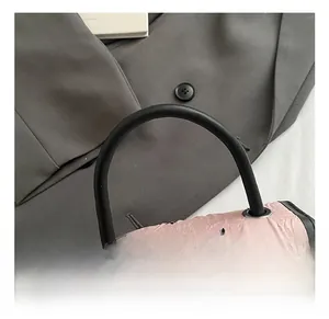 Detail of pink quilted handbag with black bow prints and a sleek cylindrical handle