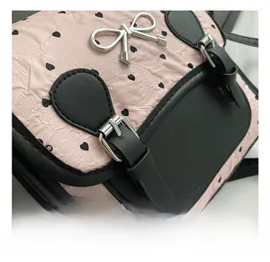 Detail aus rosa Herzmuster-Stoff und silbernem Bogen-Anhänger an einem Damenrucksack