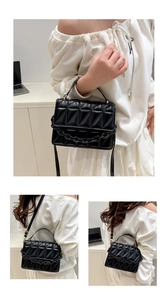 Detail of black geometric quilted crossbody bag with acrylic chain and top handle