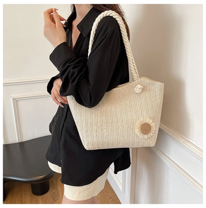 Detail of beige straw tote bag with cotton rope handles and floral flower appliqué