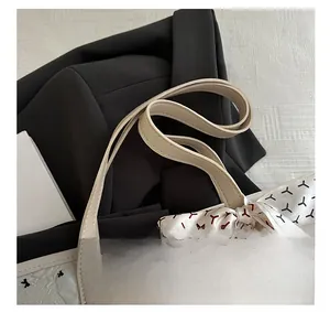 Gros plan du sac cabas blanc avec relief floral, poignée en cuir et foulard en soie à motifs