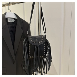Detalle de bolso negro con flecos, remaches plateados y textura de piel sintética granulada