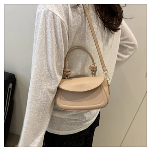 Detail of minimalist cream beige leather handbag showing knot handle and shoulder strap