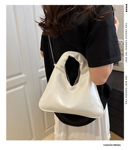 Detail view of white glossy patent leather hobo bag with sleek metal chain strap