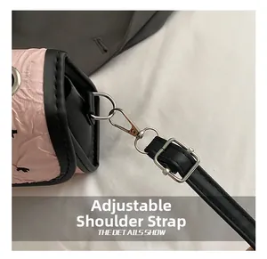 Close-up of adjustable black shoulder strap with silver metal hooks on pink pleated bag