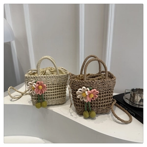 Detail of hand-woven straw bags with floral decor, drawstring liners and crossbody straps