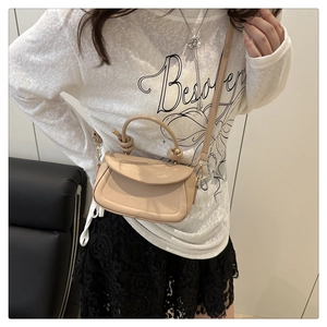 Detail of beige crossbody bag with a knot handle and golden metal buckle clasp
