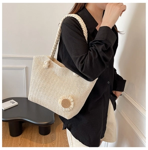 Close-up of beige woven straw tote bag with daisy floral details and cotton rope handles