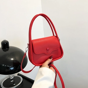 Elegant red leather handbag with lychee texture and round buckle held by a model