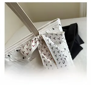 Gros plan détaillé du sac cabas en jacquard crème avec ruban décoratif en soie