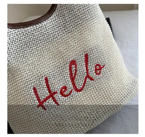 Detail of woven fabric texture with brown leather trim and red Hello embroidery