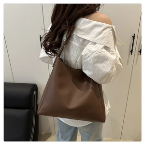 Rear view of model wearing a deep brown leather tote bag showing large capacity and straps