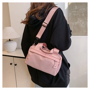 Petit sac bandoulière rose minimaliste porté par un mannequin dans un intérieur chaleureux