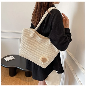 Detail of straw woven tote with white rope handles and sunflower applique charm