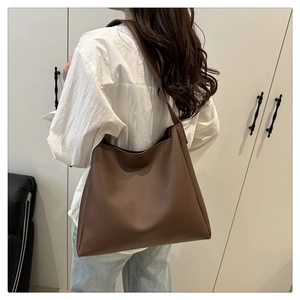 Detail view of large dark brown leather tote bag worn by model for daily commute