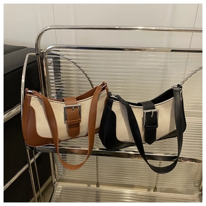 Detail of canvas shoulder bags with leather trim and large silver metal buckles