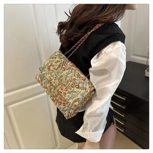 Detail of floral embroidery on a rectangular crossbody bag with woven chain strap