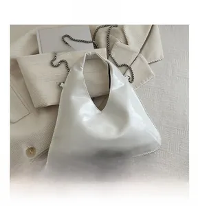 White triangular leather bag showing internal capacity with silver chain strap
