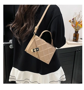 Detail of light beige quilted crossbody bag with gold chain and black lock on a model