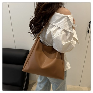 Detail view of large caramel brown leather tote bag showing crossbody shoulder strap style