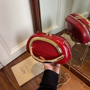 Chic red glossy leather clutch bag with golden metal handle and chain strap on wood floor