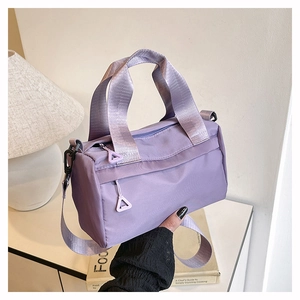 Détail macro du sac polochon en nylon lilas avec une tirette de zip triangulaire