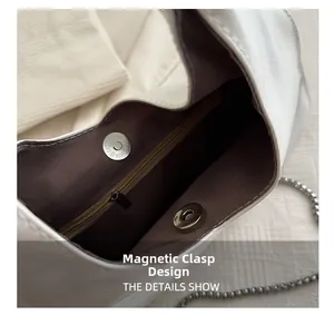 Detail view of the magnetic snap closure and inner zipper pocket of the white triangle bag