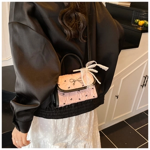 Detailed view of pink pleated mini bag with metal bow and pearl lace ribbon charm