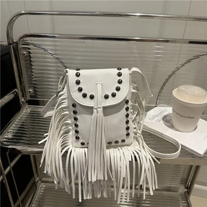 Vintage white fringe crossbody bag with black rivets and litchi texture on a shelf