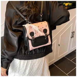 Détail d'un mini sac à dos rose et noir avec nœud en dentelle et pendentif perle