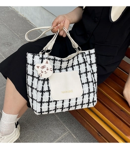 Detail view of checkered tote bag with white leather pocket and cute tiger charm