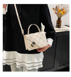 Detail of white quilted square bag with black-gold buckle and chain strap