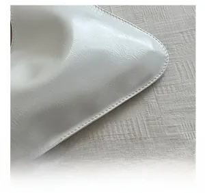 Close-up of precise stitching on white leather bag showing natural grain texture