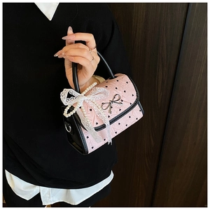 Detailed shot of pink heart-patterned bag with metal bow and lace pearl handle