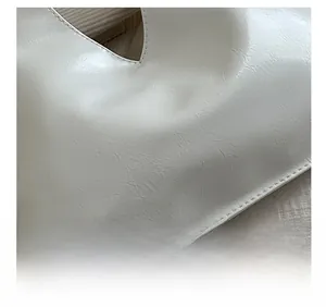 Close-up of white PU leather texture and neat stitching on a chain crossbody bag