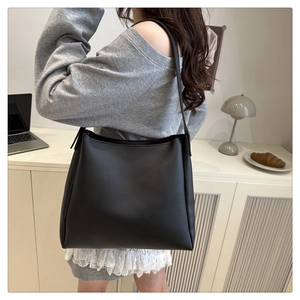 Minimalist black matte leather tote bag styled on a shoulder in a modern indoor setting
