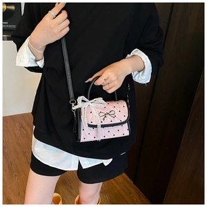 Detailed macro view of pink quilted handbag with heart prints and pearl lace charm