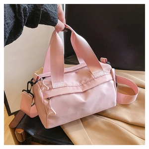 Détail du sac polochon en nylon rose montrant les poignées et la poche latérale zippée