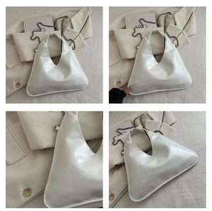 Detail of white patent leather triangle handbag with silver chain and minimalist design