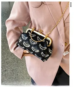 Detailed view of black evening bag featuring sequined wave patterns and golden clasp