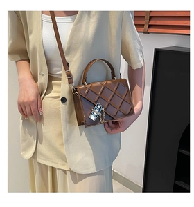 Detail of dark brown crossbody bag featuring 3D geometric quilted pattern and metal lock