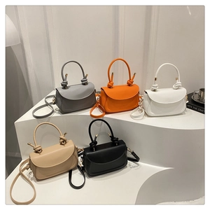 Five minimalist matte leather handbags in neutral colors on geometric display stands