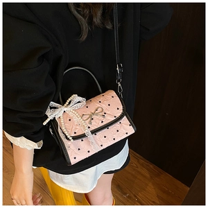 Detail of pink quilted handbag featuring black heart prints and silver bow buckle
