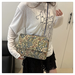 Detail of vintage floral jacquard shoulder bag with mixed chain and blue ribbon strap