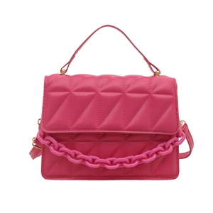 Magenta quilted crossbody bag with acrylic chain link and top handle on white background