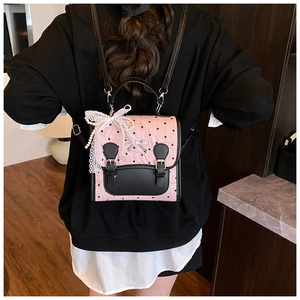 Détail du sac à dos rose et noir à motif cœurs avec nœud en dentelle et chaîne de perles