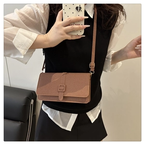 Détail d'un sac bandoulière vintage marron avec texture verticale et rabat à boucle