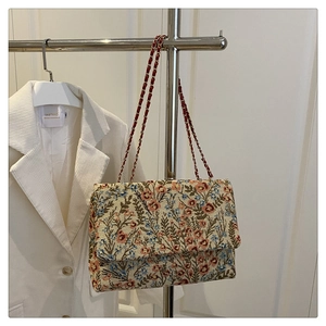 Close-up of floral jacquard underarm bag with red leather interwoven chain strap detail