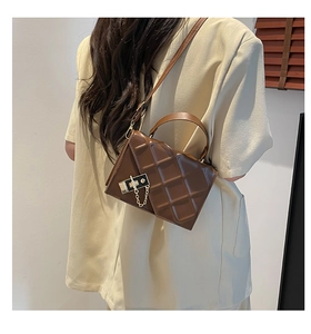 Detailed side view of brown quilted crossbody bag with gold hardware and top handle