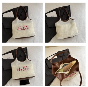 Detail view of straw tote with Hello embroidery, faux leather trim, and interior lining